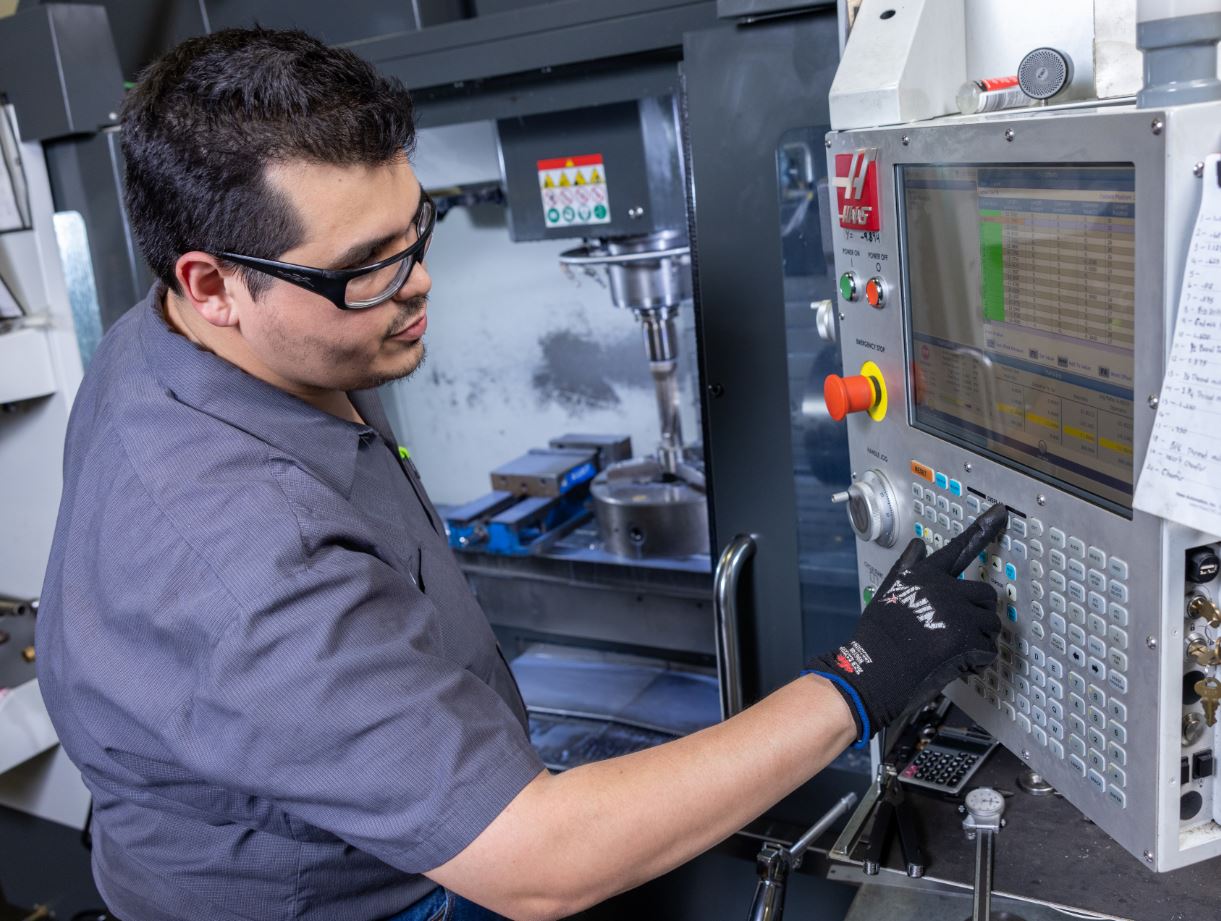 J&J Alloys employees operates CNC machine to create custom parts.