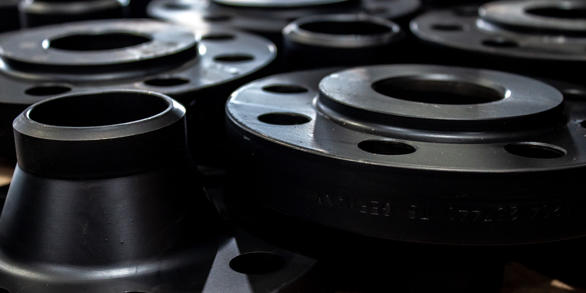 Carbon steel low temp flanges arranged in a pattern inside a warehouse.