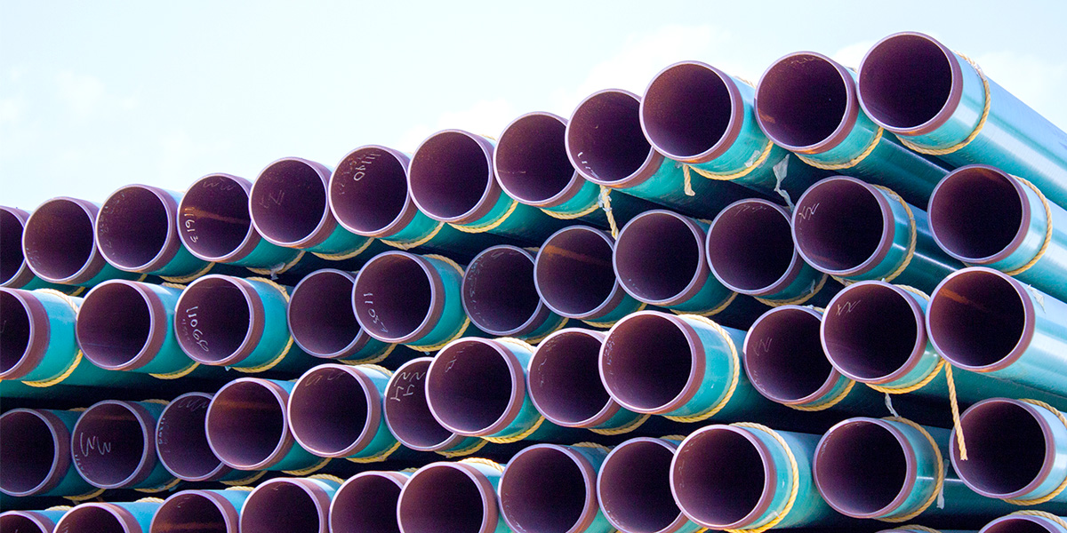 Fusion Bond Epoxy (FBE) coated carbon steel pipe arranged in stacks.